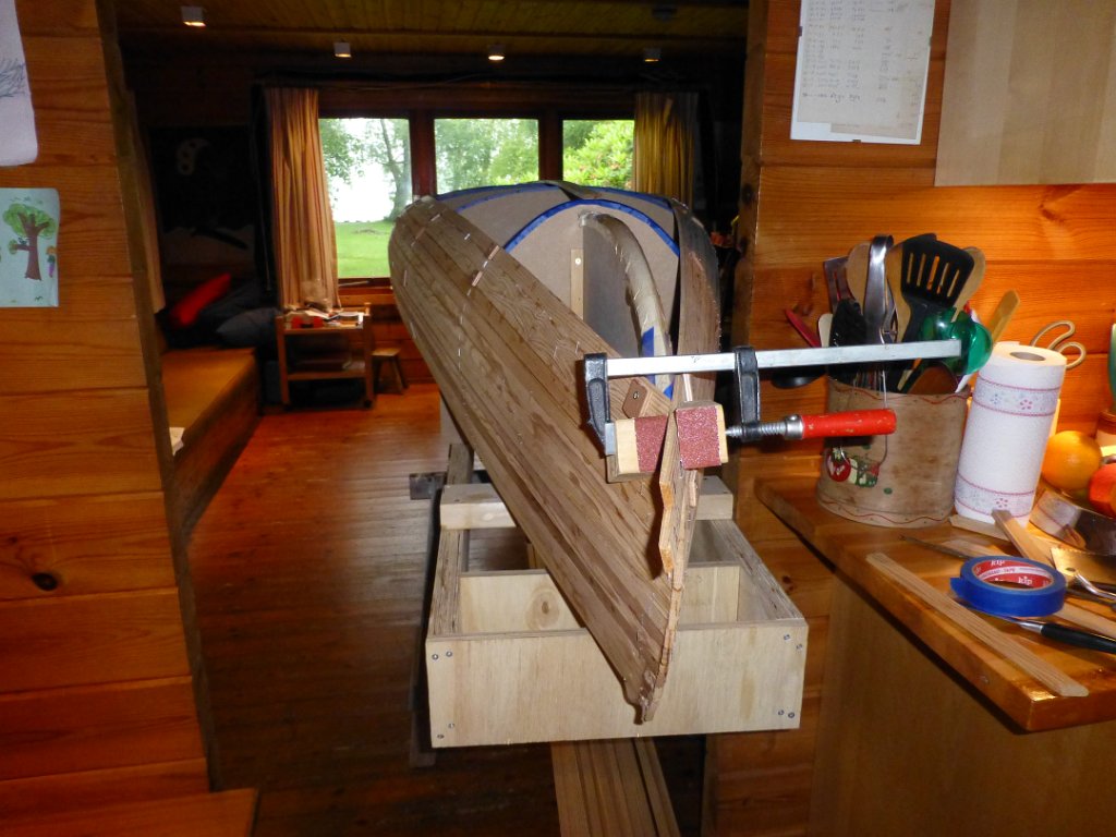 Wabnaki Canoe Build 06.JPG - En ook de boegjes vallen niet mee. Om ze goed tegen elkaar te fixeren, met zo min mogelijk schroeven, lijmen we de latjes aan elkaar vast. De boeg steekt uit in de keuken.